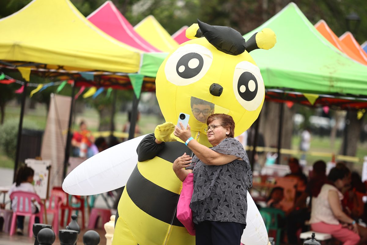 Una señora se toma una selfie con la botarga de abeja del festival
