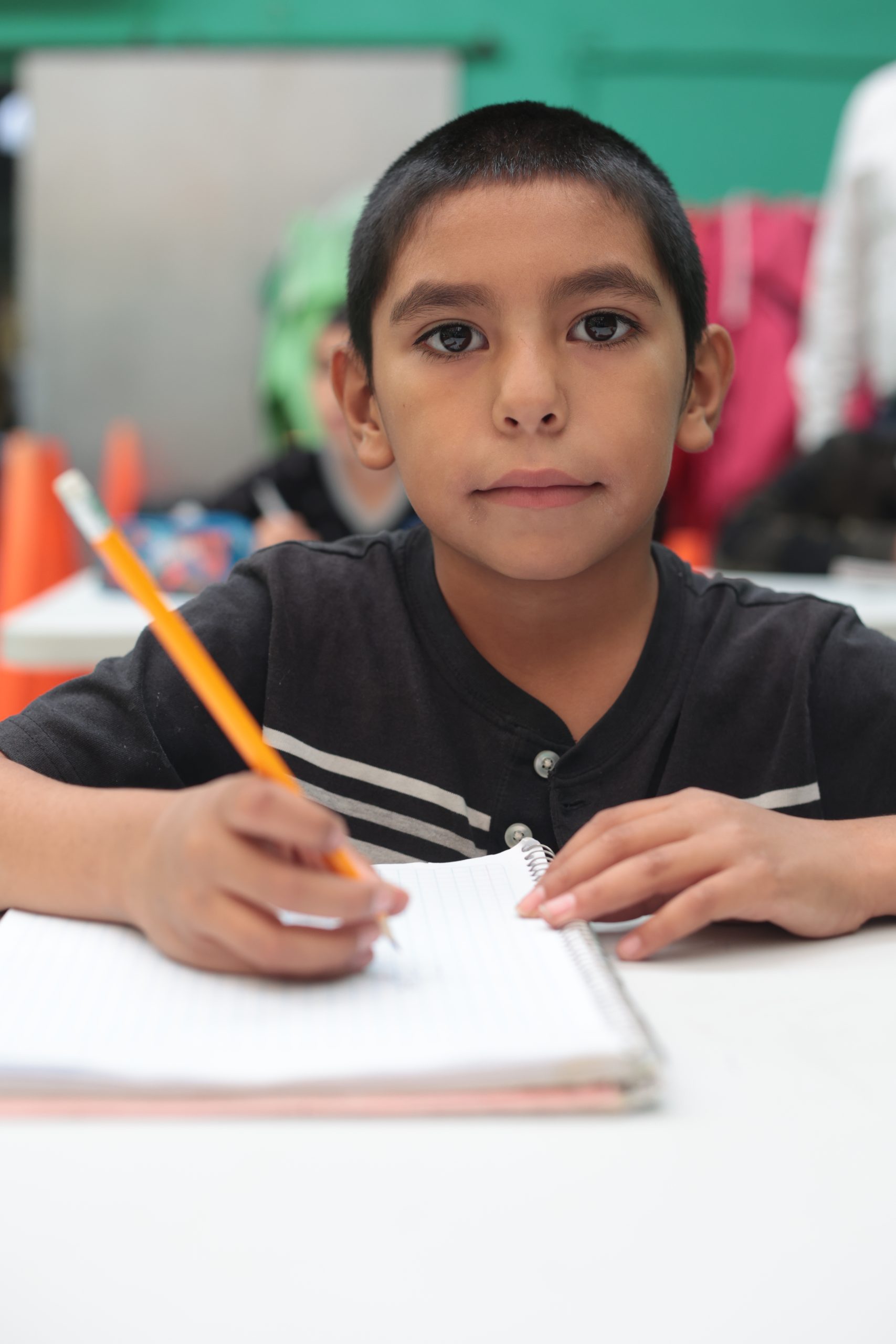 Niño de Hualiches escribiendo en su cuaderno durante el curso